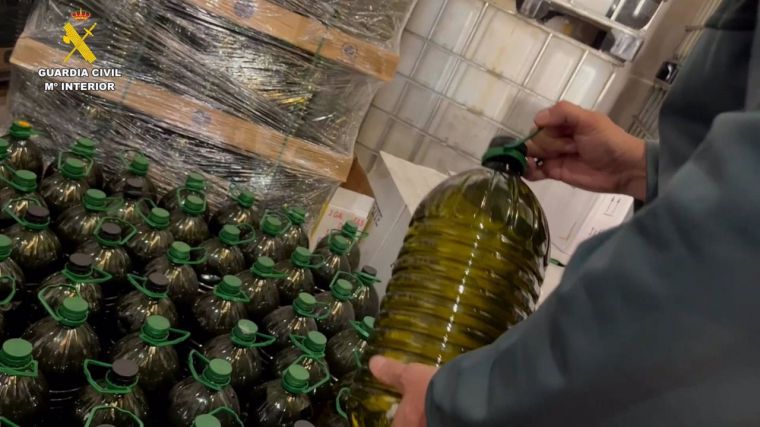 Agente de la Guardia Civil con las garrafas de aceite de oliva interceptadas durante la operación OPSON XII en España